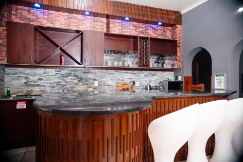 a bar in a restaurant with two white chairs at Falcon Lodge (S) in Bela-Bela
