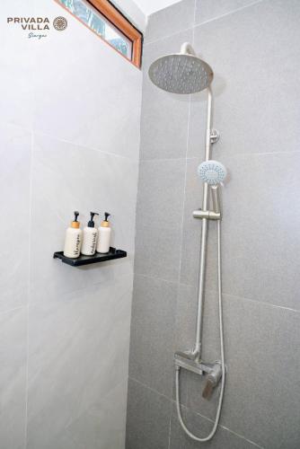 a shower with three bottles on a shelf in a bathroom at Privada Villa Siargao in General Luna