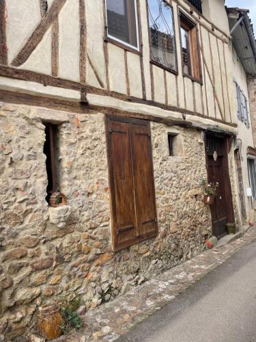 a stone building with a wooden door on a street at Maison de caractère in Les Bordes-sur-Arize