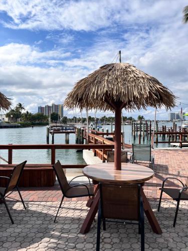 a wooden table with a straw umbrella on a pier at Blue Heron Bridge Hotel and Dive Club in Riviera Beach