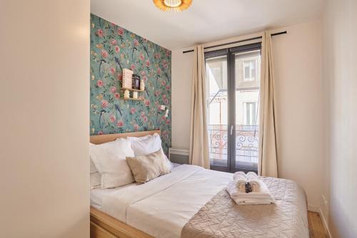 a bedroom with a bed with towels and a window at Residence Boulogne Centre le passage by Studio prestige in Boulogne-Billancourt