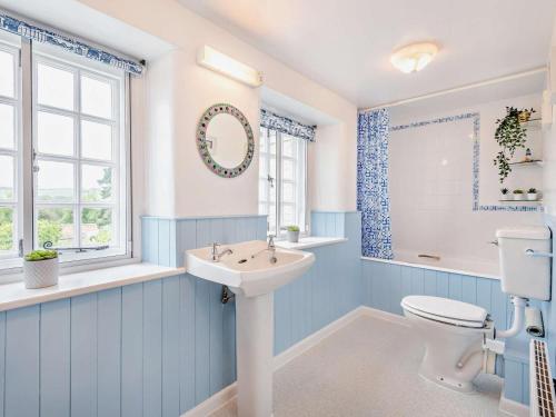 a blue and white bathroom with a toilet and a sink at 4 Bed in Wareham oc-dc125 in Corfe Castle