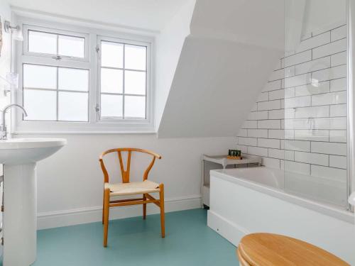 a bathroom with a sink and a tub and a chair at 4 Bed in Bridport oc-dc083 in West Bay