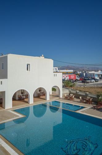 a large swimming pool in front of a white building at Perla Hotel in Agios Prokopios