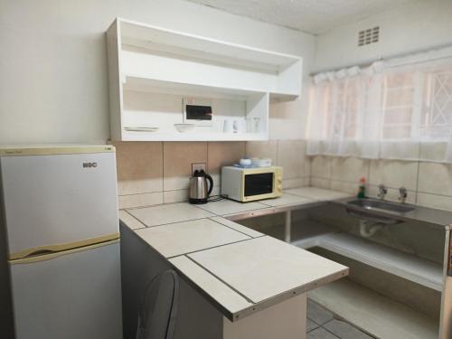 a small kitchen with a refrigerator and a microwave at Cozy Flat in East London