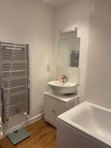 a bathroom with a sink and a tub and a mirror at 2 Bed apartment- Laindon in Great Burstead