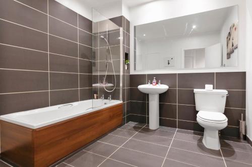 a bathroom with a tub and a toilet and a sink at The Clydesider in Glasgow