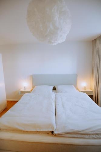 a white bed in a room with two lamps at Emsperle in Rietberg