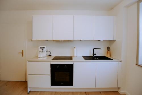 a white kitchen with white cabinets and a sink at Emsperle in Rietberg