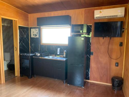 a kitchen with a black refrigerator and a sink at L a N e g r a in Barra de Portezuelo