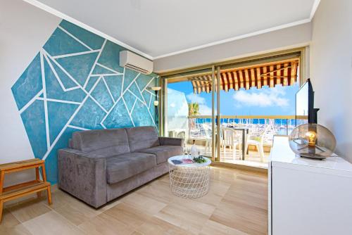 a living room with a couch and a kitchen with a view at Vue mer port de garavan in Menton