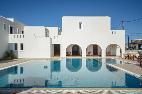 a swimming pool in front of a white building at Perla Hotel in Agios Prokopios