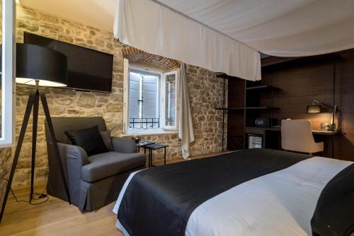 a bedroom with a bed and a couch and a tv at Murum Heritage Hotel in Split