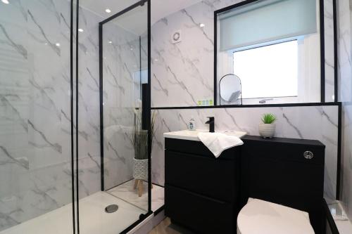 a bathroom with a shower and a sink and a mirror at Modern 2 Bedroom Cottage Flat in Stenhousemuir