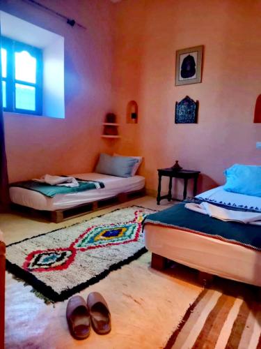 a bedroom with two beds and a pair of shoes at Dar INNÂ in Aït Benhaddou