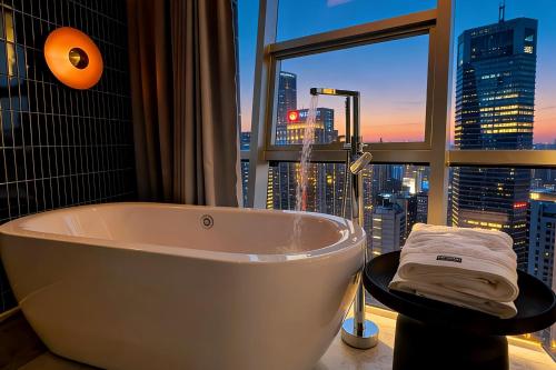 a bath tub in a bathroom with a view of a city at Chongqing IBESHO HOTEL in Chongqing