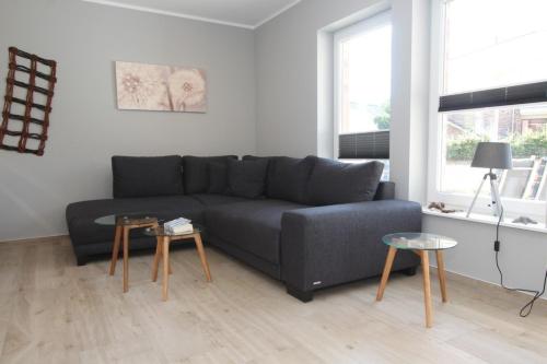 a living room with a gray couch and two tables at Ferienhaus Skanhuus in Klütz