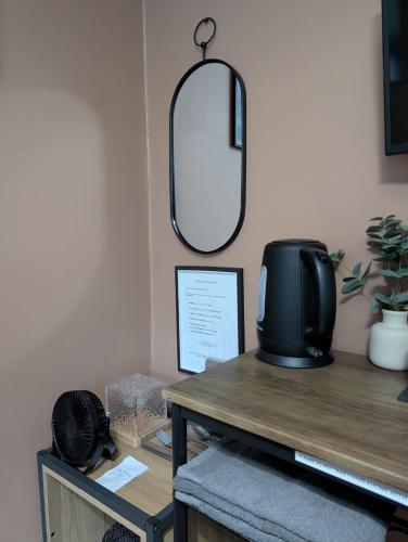 a mirror on the wall above a desk with a television at R3 - Cozy Small Double - City & Beach Access, WIFI, Free Parking, Bus Stop 50ft From House - Self Catering in Swansea