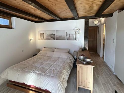 a bedroom with a large bed and a wooden ceiling at Le Studio du Rhône in Saint-Léonard