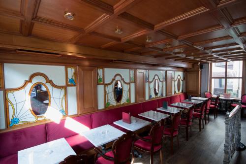 a row of tables in a restaurant with red chairs at Hotel Ovo malo duše in Sarajevo