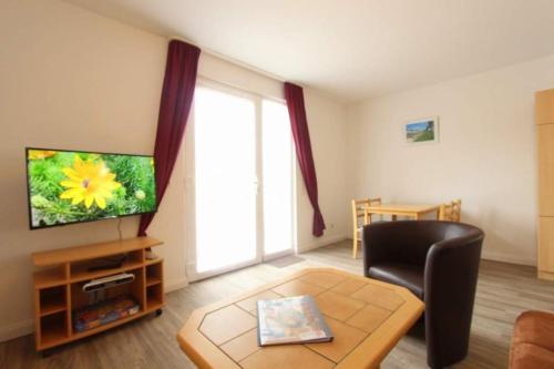 a living room with a television and a chair at Bungalow Marina Tarnewitz in Tarnewitz