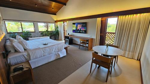 a bedroom with a bed and a desk and a table at Pousada Casa do Forte in Praia do Forte