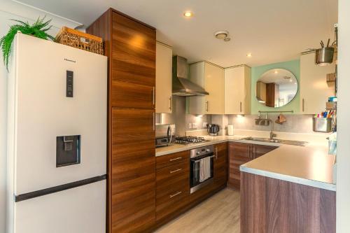 a kitchen with a white refrigerator and wooden cabinets at Bond Central - City Centre Oasis in Southampton
