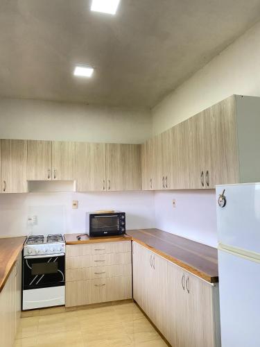 a kitchen with wooden cabinets and a white refrigerator at Alquilo Casa por Día in Cambyretá