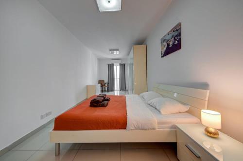 a bedroom with a large bed with an orange blanket at Central, spacious apartment with Sea Views in St. Paul's Bay