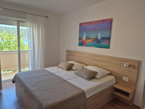 a bedroom with a large bed with a painting on the wall at Apartments Poljak in Supetarska Draga