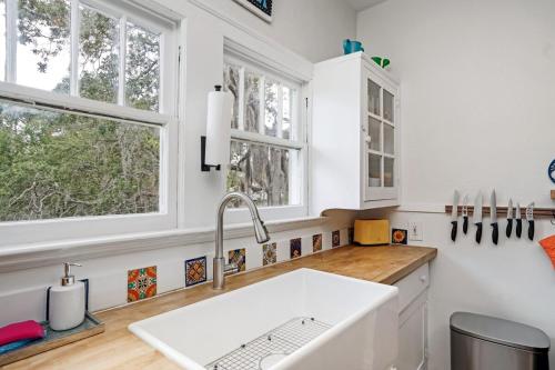 a white kitchen with a sink and windows at Colorful waterside home in Bradenton