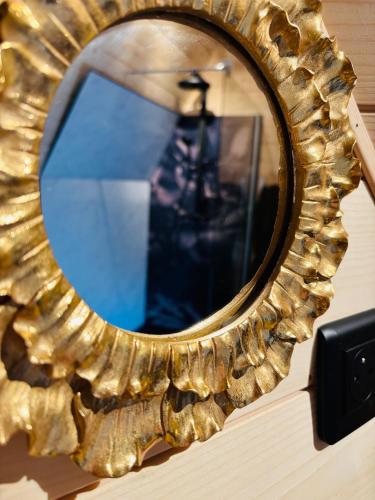 a gold mirror on a wall with a reflection of a lighthouse at La Clé de L Insolite in Hudiviller