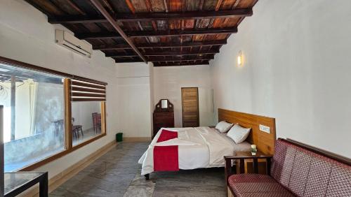 a bedroom with a bed and a couch in a room at Vayuvana Heritage Organic Farm Resort in Panamaram