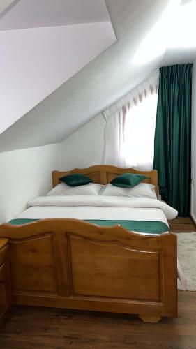 a bedroom with a wooden bed with green curtains at Pensiunea Lavinia Daniel in Borşa