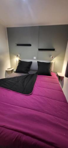 a bedroom with a large bed with purple sheets at Bungalow le Sartène in Lumio