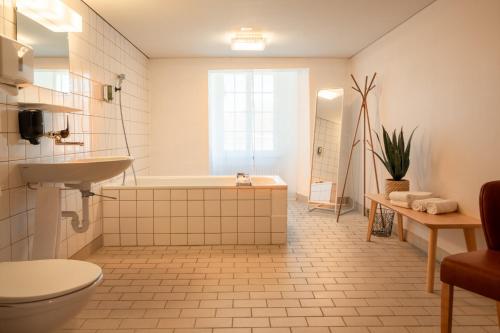 a bathroom with a tub and a toilet and a sink at BnB SchlafSchloss in Sumiswald