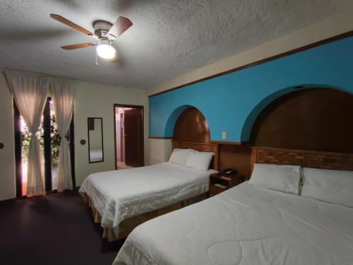 ein Hotelzimmer mit zwei Betten und einem Deckenventilator in der Unterkunft Posada Tolosa in Zacatecas