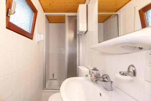 a white bathroom with a sink and a toilet at Ferienhaus am Strand 92a - Bade- & Saunawelt täglich inklusive in Baabe