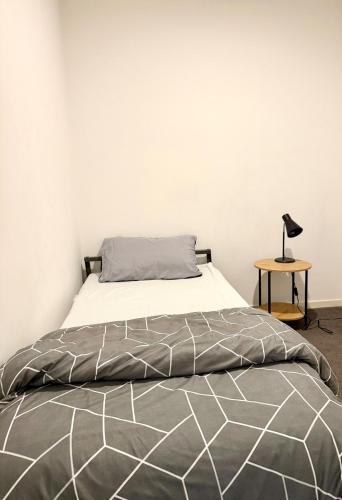 a bed with a gray and white comforter and a lamp at Premium Apartment with 2 Beds 1 Bath in Melbourne