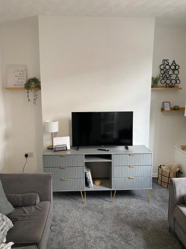 a living room with a flat screen tv on a entertainment center at Slick Space for a Wigan Stay - 5 Minutes from M6 and M58 Motorways in Pemberton