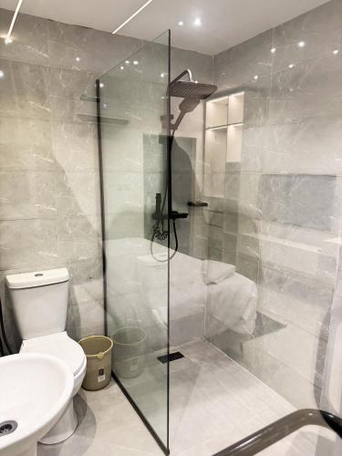 a bathroom with a toilet and a glass shower at MAISON 9 Apartments Surulere in Lagos
