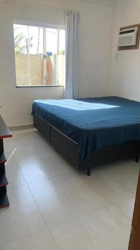 a bedroom with a bed with a blue blanket on it at Casa aconchegante com piscina e garagem dupla in Búzios
