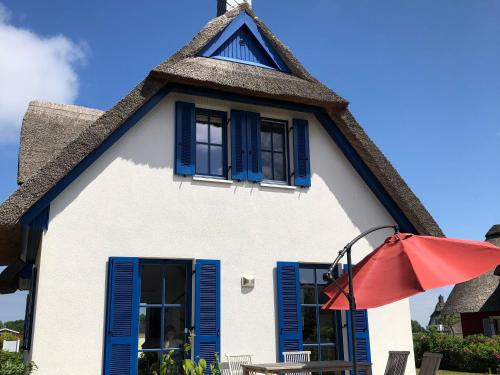 a house with blue shutters and a red umbrella at Reethaus "Alinde" in Zierow