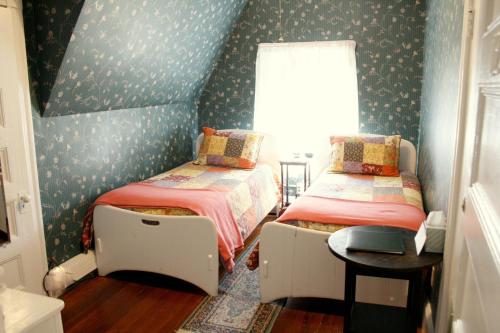 two beds in a small room with wallpaper at The Coolidge Corner Guest House: A Brookline Bed and Breakfast in Brookline