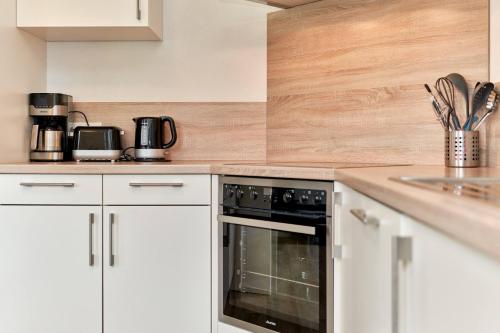 a kitchen with white cabinets and a black oven at Der Wattläufer in Ockholm