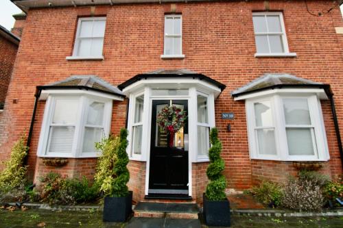 a red brick house with a black door and two windows at No.10 @ ShortStays Serviced apartments in Basingstoke