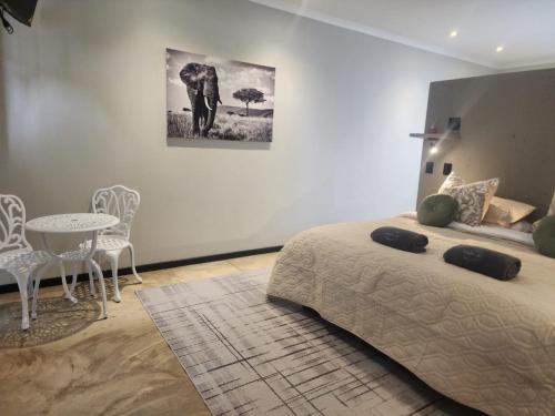 ein Schlafzimmer mit einem Bett, einem Tisch und einem Bild eines Elefanten in der Unterkunft Charlen's Rest in Windhoek
