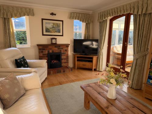 a living room with a couch and a tv and a table at Oak Tree Cottage, Charming, Rural New Forest Home in Boldre