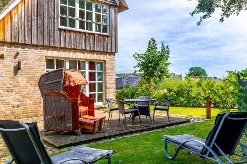 a patio with a table and chairs and a grill at Reethaus Ostseeblick 1 in Wohlenberg