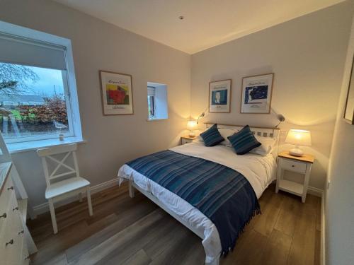 a bedroom with a bed with two lamps and a window at Stable Cottage in Lockerbie